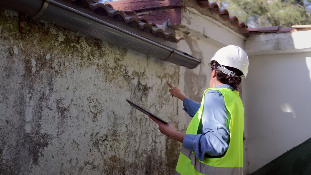 Worker in safety vest documenting damage during a property maintenance inspection